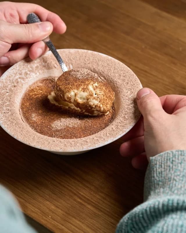 Tiramisú de Asiático servido en un plato de cerámica, con una cuchara