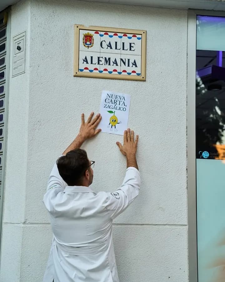 Ismael Expósito pegando un cartel de «Nueva carta, Zagálico» bajo la placa de la calle Alemania